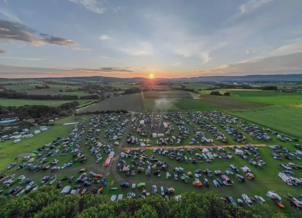 Luftbild vom DACHZELT FESTIVAL bei Sonnenuntergang mit hunderten Fahrzeugen auf der Wiese