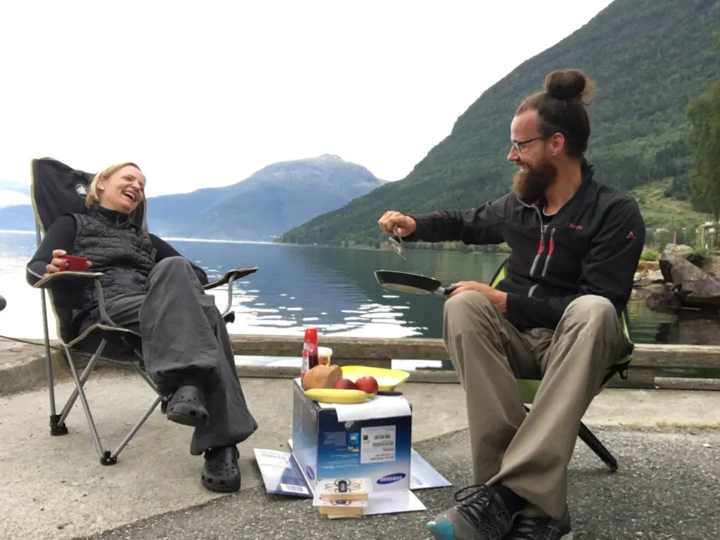 Mann und Frau unterhalten sich Campingmöbel berge und wasser im hintergrund