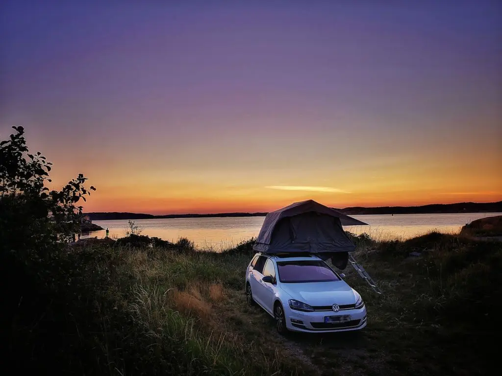 Dachzelt auf Auto bei sonnenuntergang am wasser