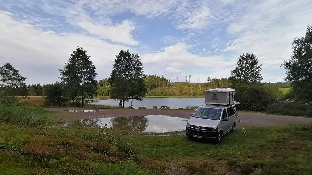 Autohome Maggiolina weiss auf einem weissen Auto See Bäume bewölkter Himmel