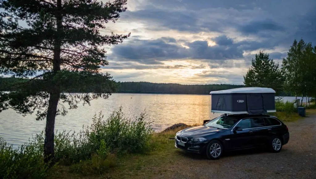 Hartschalendachzelt viereck auf dem auto an einem see geparkt sonnenuntergang bewälkter himmel