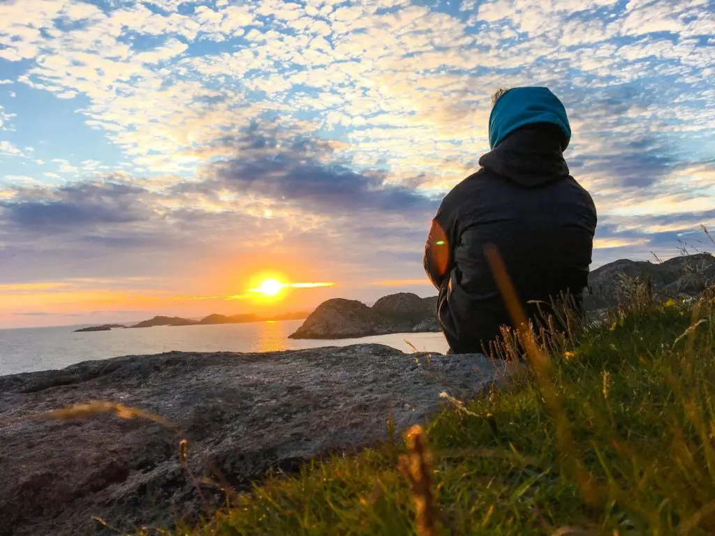 mann geniesst sonnenuntergang fjord hügel