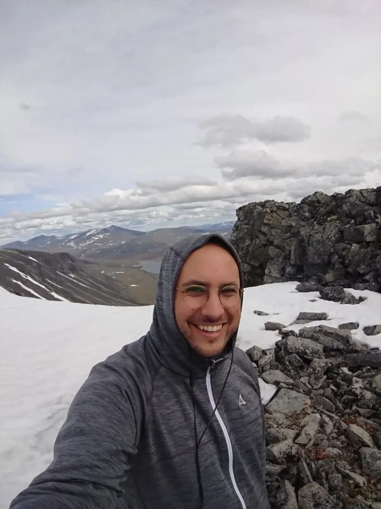 Mann vor einem Schneefeld mit Bergen im Hintergrund