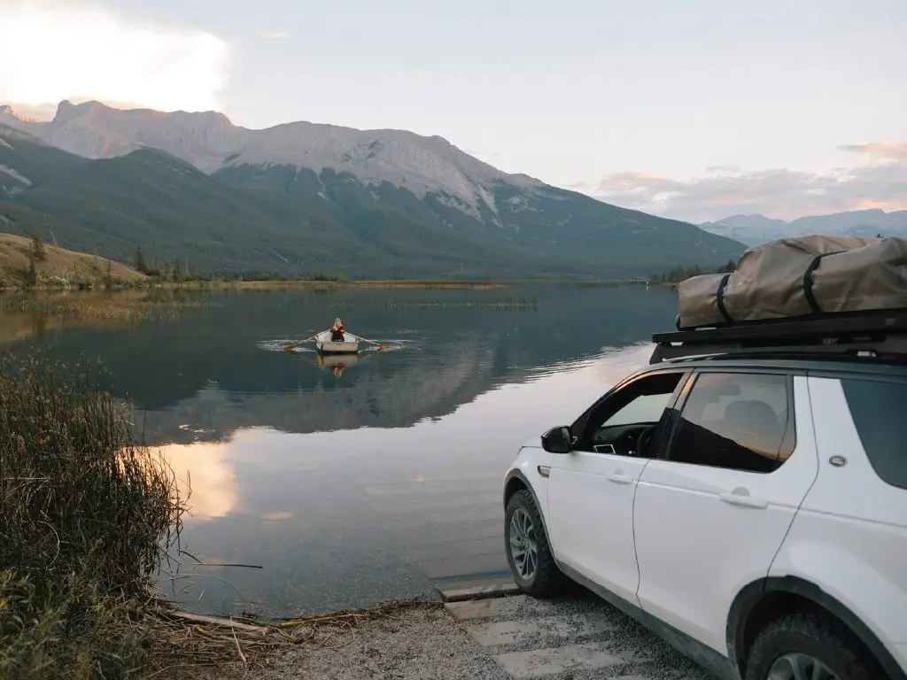 weisses auto mit zugeklapptem dachzelt von front runner feather-lite berge fluss