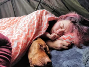 Frau und Hund im Dachzelt zugedeckt mit einer Decke