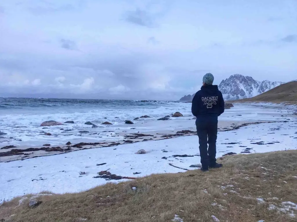 Frau mit muetze meer schnee sand bewölkter himmel