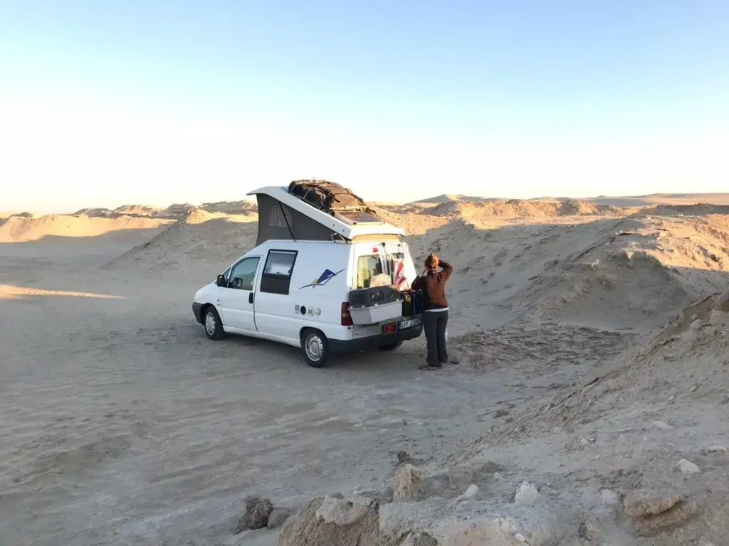 Frau auto mit dachzelt steinwueste weite blauer himmel