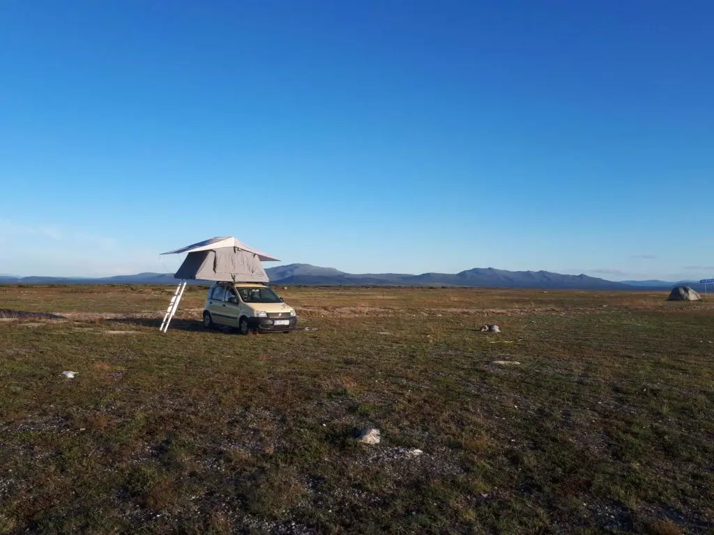 auto mit dachzelt weite blauer himmel sandiger erdiger boden