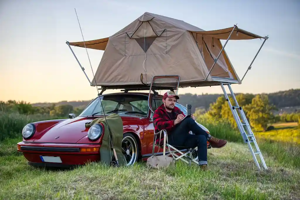 Dachzelt finden Autocamp trophy pioneer auf rotem sportwagen mann lesen sonnenuntergang natur