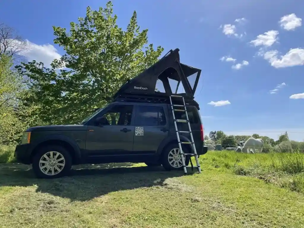 BamDach Dachzelt Alu Passion auf einem Geländewagen blauer himmel grüne wiese baum