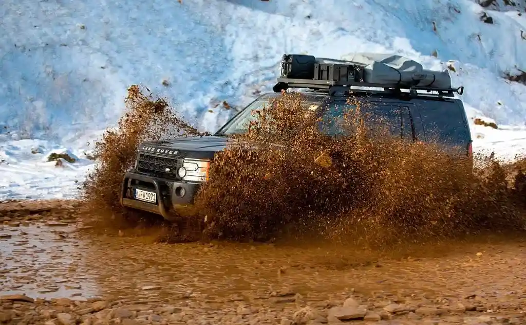 Offroad Zubehör Geländewagen mit Dachzelt fährt durch den schlamm winter schnee im hintergrund