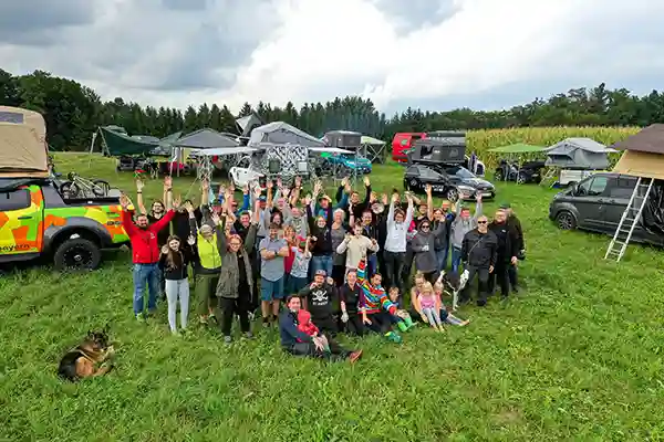 Luftaufnahme dachzelt meetup oberbayern menschen im vordergrund autos mit dachzelten im hintergrund grüne wiesen bedeckter himmel