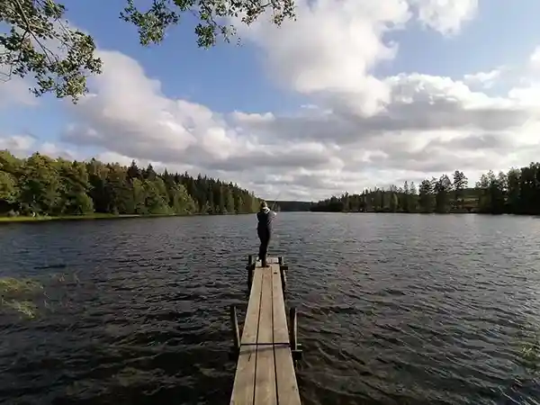 Frau beim Angeln auf einem Steg, See Wald