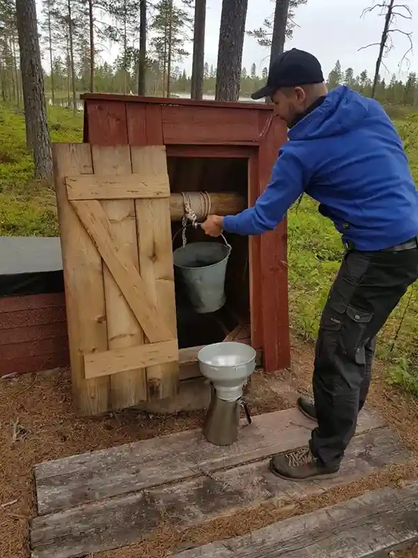 Mann schöpft Wasser aus einem Brunnen