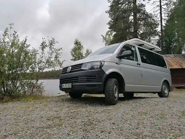 weisses hartschalendachzelt auf weissen auto bäume bewölkter himmel