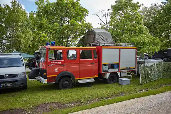 feuerwehr auto mit dachzelt baeume wiese 