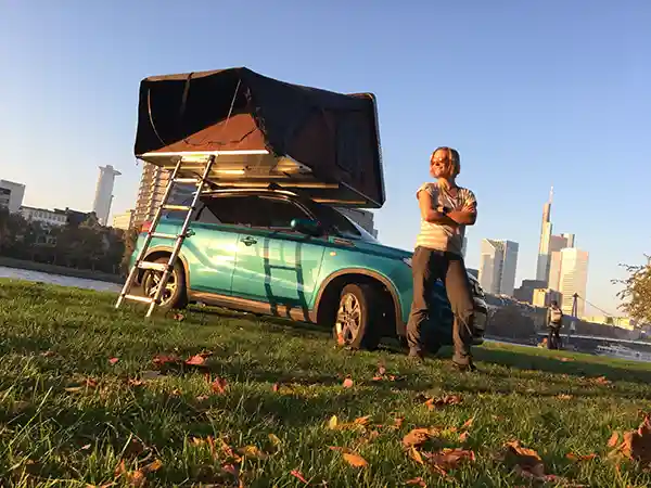 alleine reisen frau suzuki mit ikamper hybriddachzelt blauer himmel wiese