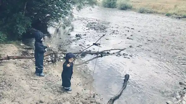 kinder am Fluss spielen mit holz