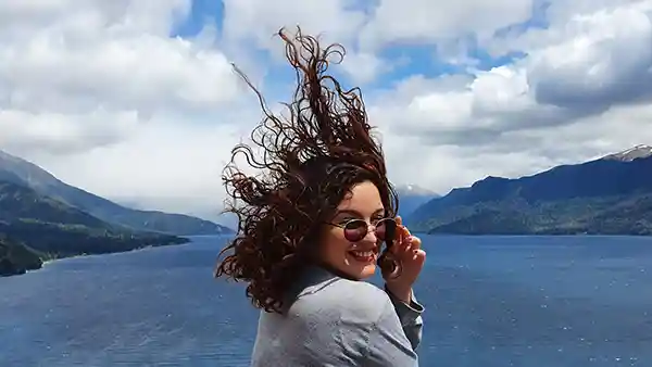 frau mit wind in den haaren an einem see