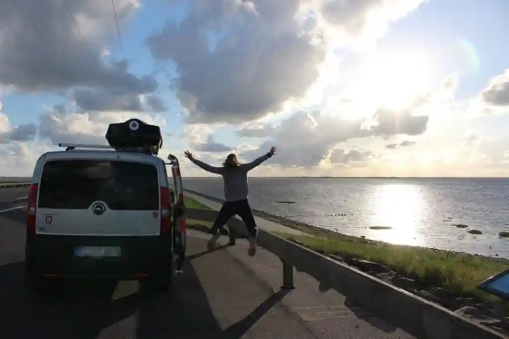 Frau Auto mit Dachzelt wasser wolken abendstimmung