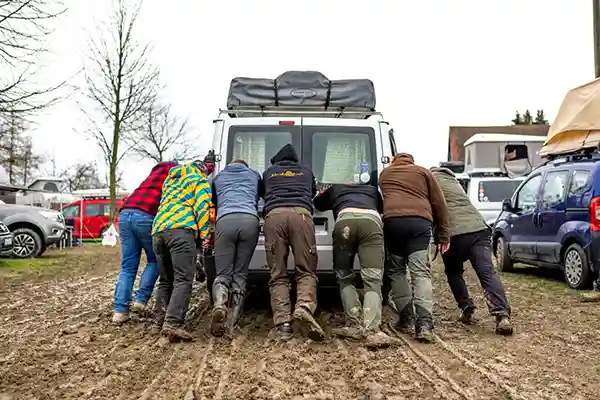 Dachzeltnomaden schieben ein Auto aus dem Schlamm