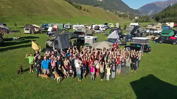 Luftaufnahme dachzelt meetup schweiz menschen im vordergrund autos mit dachzelten und berge im hintergrund