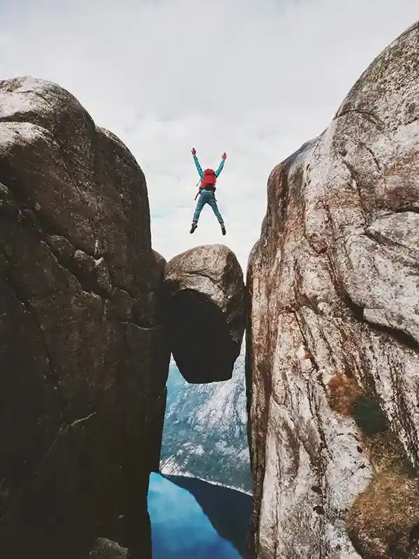 eingeklemmter Felsbrocken, hüpfender mensch