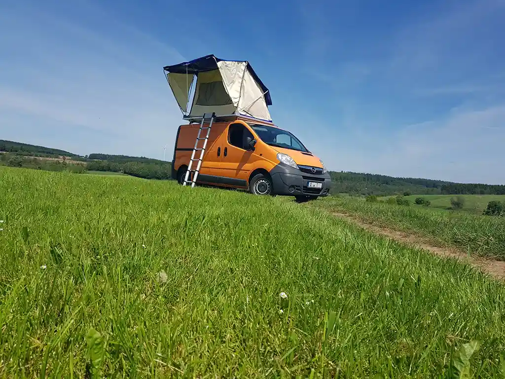 selbst gebautes dachzelt wiese oranges auto