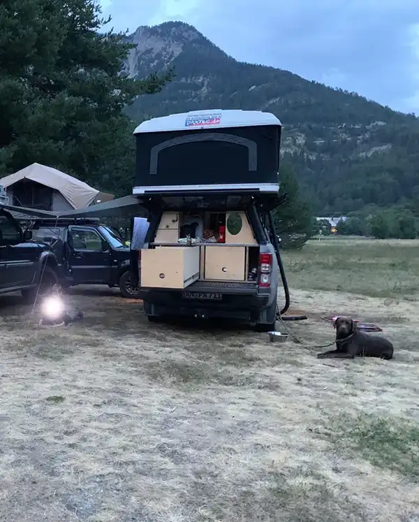 Hund neben einem ausgebauten auto mit dachzelt