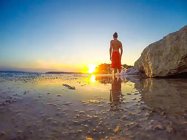 Mann geniesst sonnenuntergang am meer