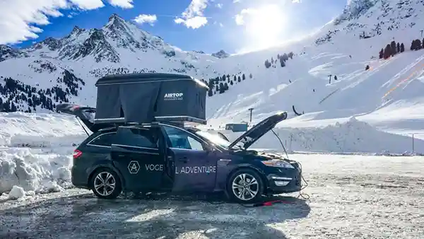 ford mondeo mit hartschalendachzelt in einer schneelandschaft sonne schnee blauer himmel berge