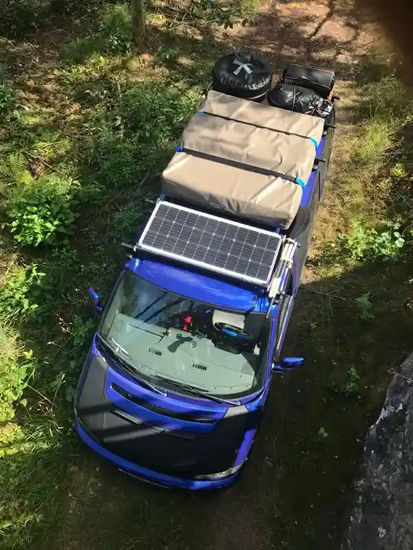 Beladenes Auto mit Solarpanel Wasserdichten kisten und dachzelt