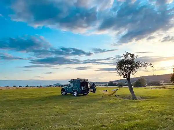 Auto mit Dachzelt wiese baum abendstimmung