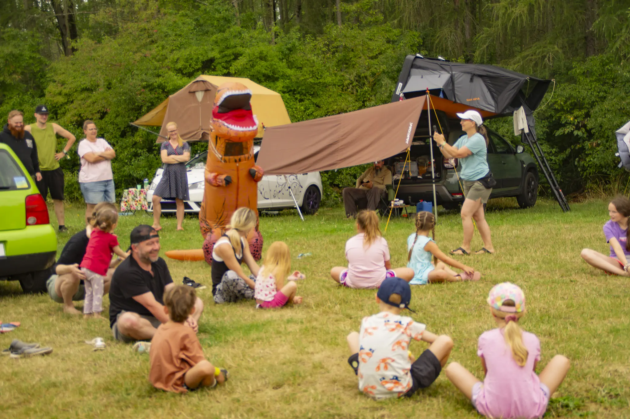 Kinder laufen dem Dino über die Campwiese hinterher